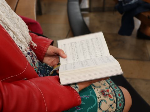 Eine Person sitzt in der Kirche und singt ein Lied. 
