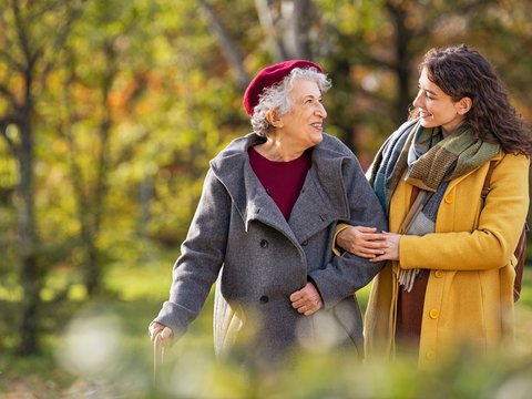 Seniorenbegleitung | © AdobeStock_Rido Man sieht eine Frau, die ihren Arm bei einer älteren Frau eingehakt hat, während beide spazieren gehen.