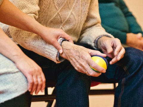 Engagement im Altenheim | © pexels_matthias zomer Man sieht eine ältere Person sitzend, die einen Apfel in der Hand hält.