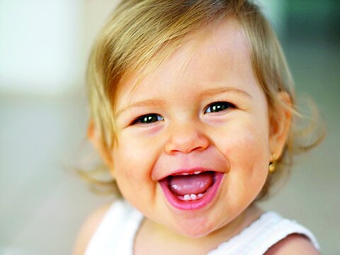 Ein kleines Kind lacht in die Kamera.