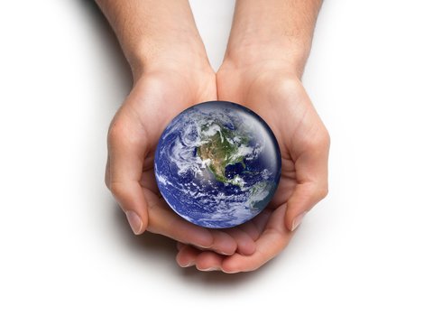 Zwei Hände halten eine kleine Version des Planeten Erde.